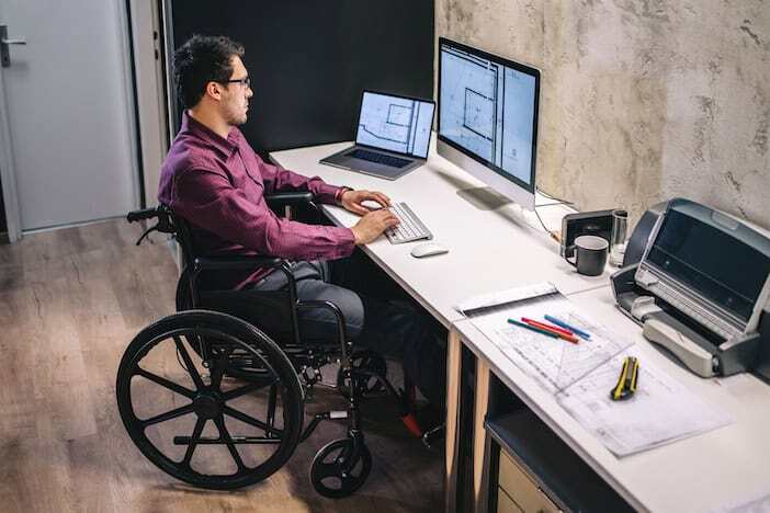 wheelchair user working at a desk in a modern office setting