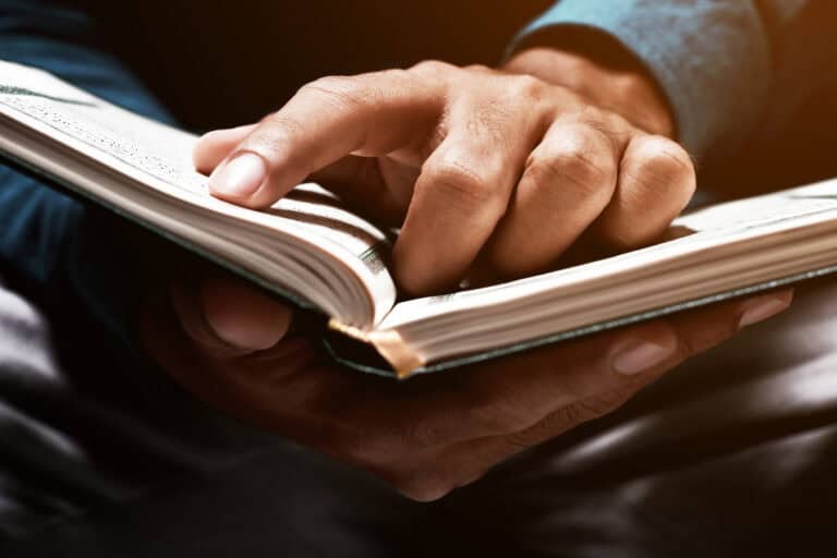 A person holding and reading a Braille book