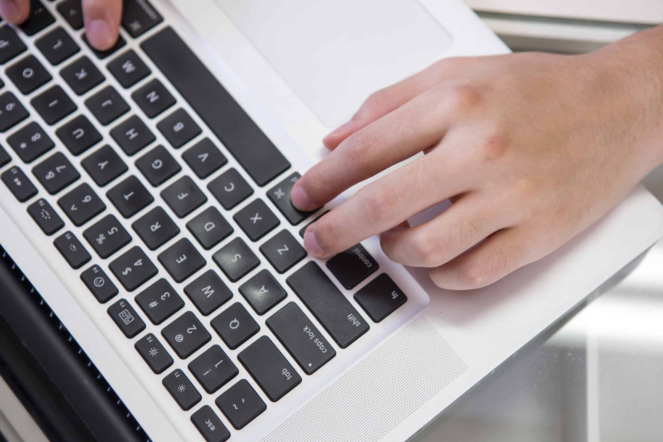 A hand resting on a laptop keyboard
